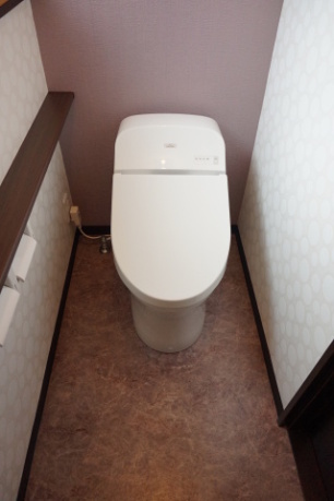 大理石をイメージした床とアクセントカラーの壁クロスが映えるトイレ室内